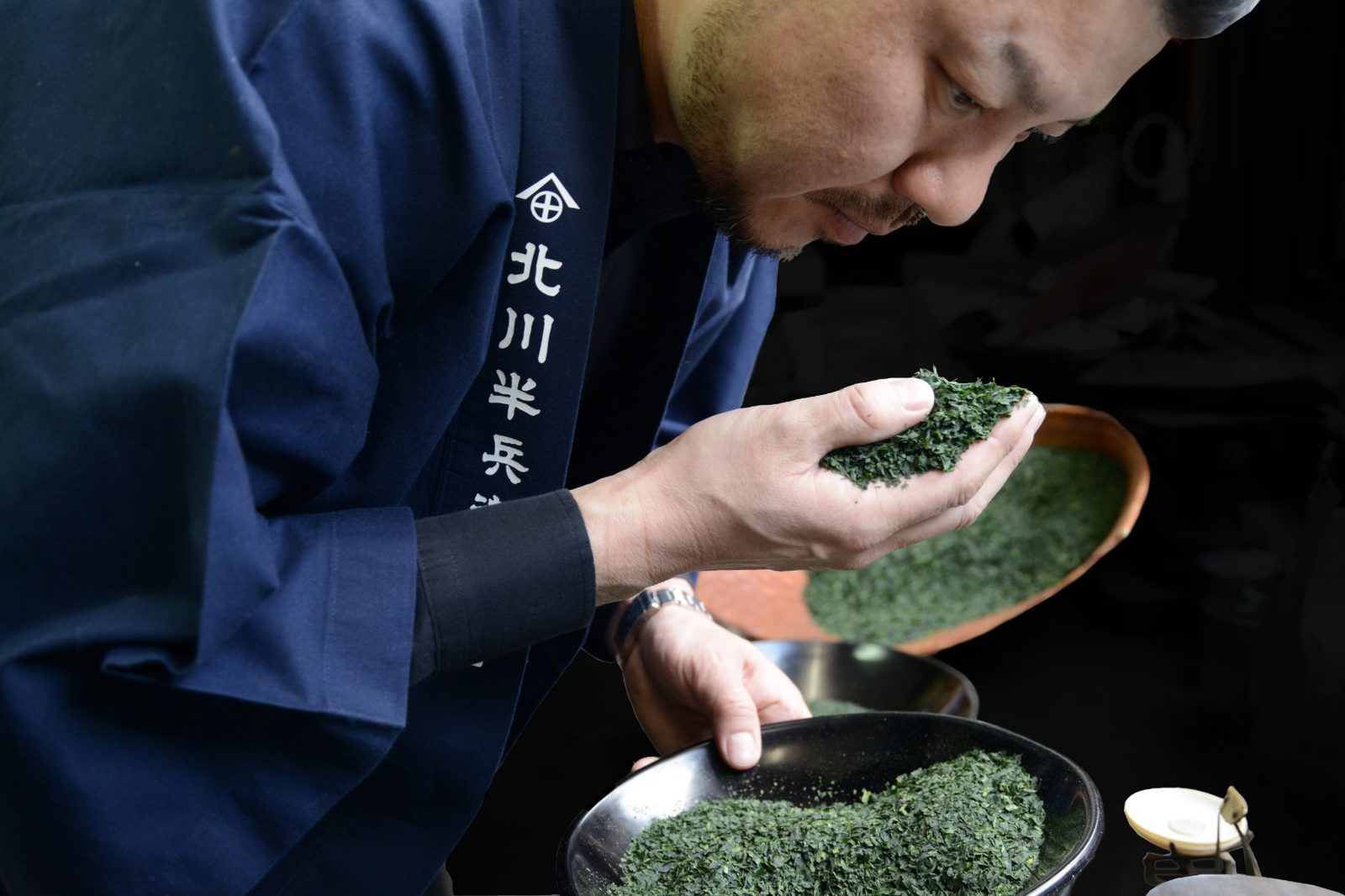 Tea master in indigo happi coat smelling loose tea leaves