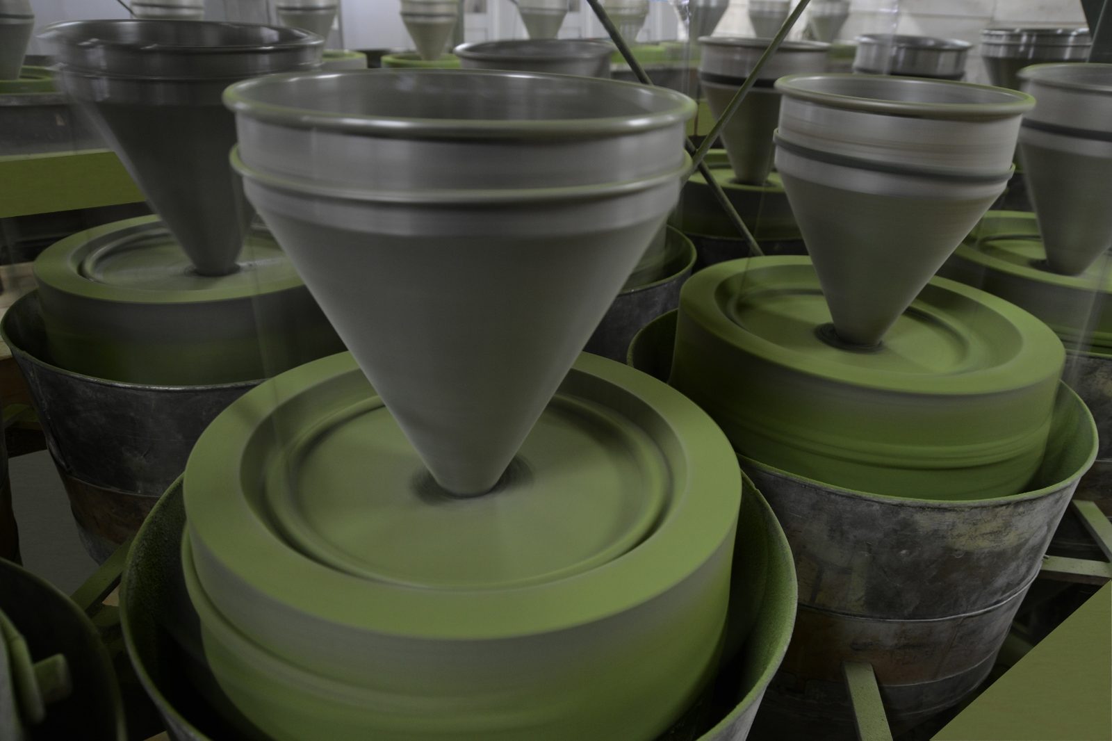Close-up of granite stone mills grinding matcha with bright green powder visible