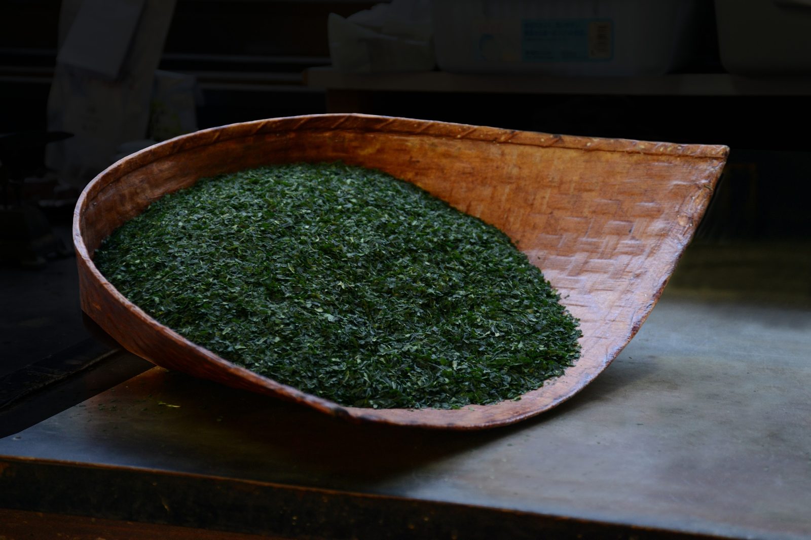Tea leaves in a traditional woven wooden basket with dramatic lighting